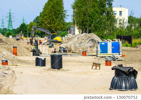 Dewatering pump and excavation site with heavy machinery and drainage pipes during construction works 130070752