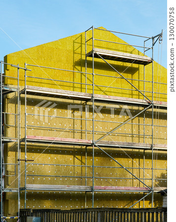 Building under renovation with thermal insulation and scaffolding for improved energy efficiency 130070758