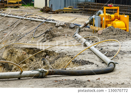 Site dewatering pump with pipes and hoses used for groundwater control at construction excavation 130070772