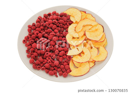 Trekking food. Freeze-dried fruit for travel. Dried apples and raspberries in a white ceramic plate isolated on a white background. 130070835