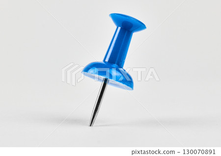 Close up of a blue pushpin placed on white 130070891