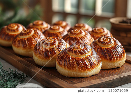 Home baked buns. Variety of baked snail-shaped buns in on a wooden trading tray on a white background. Home baked buns. Variety of baked snail-shaped buns in on a wooden trading tray on a white background. 130071069
