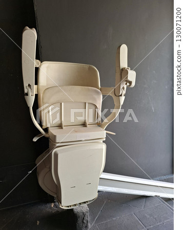 A wheelchair lift designed for easy access in a contemporary building, featuring sturdy arms and a spacious seat, ensuring mobility assistance for individuals with disabilities. A wheelchair lift designed for easy access in a contemporary building, featuring sturdy arms and a spacious seat, ensuring mobility assistance for individuals with disabilities. 130071200