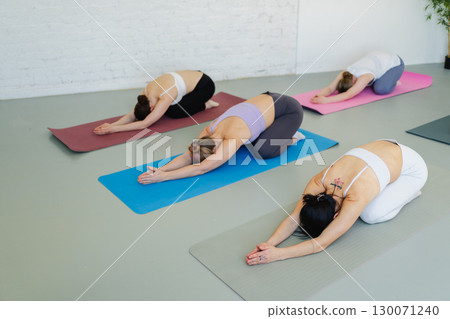 Yoga class Pilates workout. Group of sporty people doing exercise in studio class for yoga wellness mindfulness meditation. Personal trainer men women practicing yoga in gym training stretching indoor Yoga class Pilates workout. Group of sporty people doing exercise in studio class for yoga wellness mindfulness meditation. Personal trainer men women practicing yoga in gym training stretching indoor 130071240