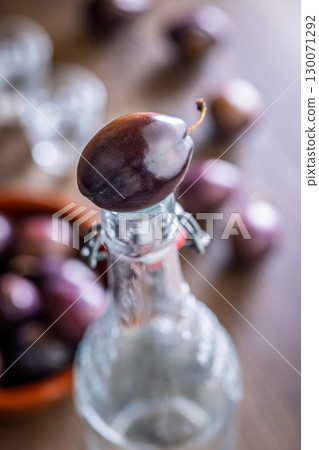 Plums and distilled alcohol on wooden table. Plum brandy shot. Plums and distilled alcohol on wooden table. Plum brandy shot. 130071292