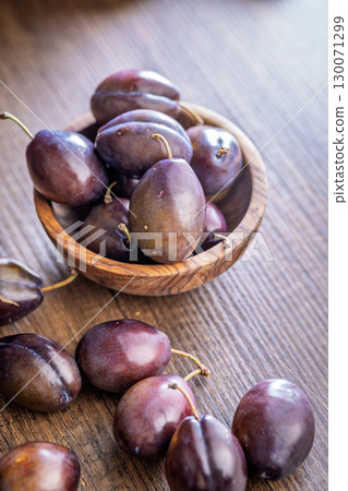 Ripe plums on wooden table. 130071299