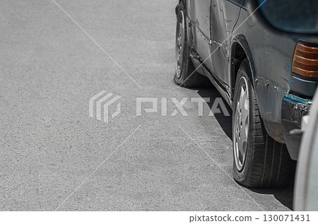 The twisted hull of the left side of the old car is dark green with dents, scratches, damage to skin elements, absence of decorative elements, the pressure in the wheels is deflated. Empty copy space 130071431