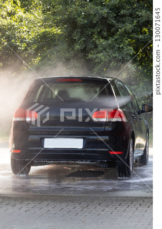 Rear view of black car under water spray Rear view of black car under water spray 130071645