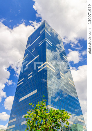 South Tower multi-storey skyscraper modernism style modern office building, facade glass curtain wall, white clouds in blue sky in Brussels city, Tour du Midi Zuidertoren tallest building in Belgium 130071659