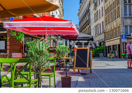Street restaurant with tables and chairs on narrow street, road with paving stone, old buildings in Antwerp historical city center, street cafe in old town Antwerpen, Belgium Street restaurant with tables and chairs on narrow street, road with paving stone, old buildings in Antwerp historical city center, street cafe in old town Antwerpen, Belgium 130071666