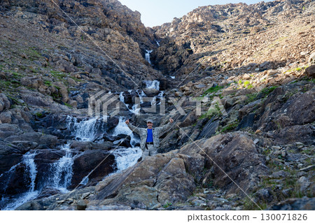 A hunter stands in a gorge next to a waterfall showing his thumbs up A hunter stands in a gorge next to a waterfall showing his thumbs up 130071826