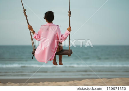 back view of carefree happy girl on swing at sea beach, nature relaxation and joyful freedom, rear perspective of woman on shore swing, coastal peace and summer leisure vacation back view of carefree happy girl on swing at sea beach, nature relaxation and joyful freedom, rear perspective of woman on shore swing, coastal peace and summer leisure vacation 130071850