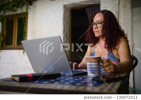 Focused Woman Working on Laptop in Outdoor Patio Setting 130072011