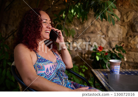 Woman Smiling While On Phone Outdoors in Relaxing Garden Setting 130072016