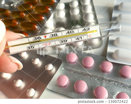 Close-Up of Medical Pills and Selected Thermometer Showing Body Temperature 130072422