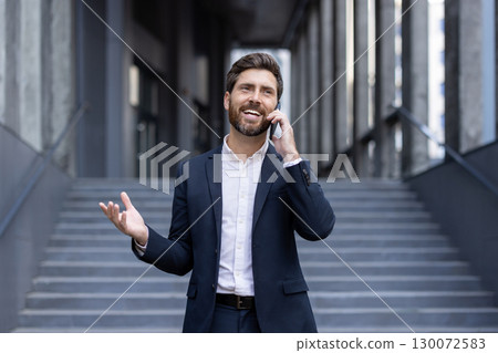 Business professional in a suit talking on a smartphone, exuding confidence outdoors in an urban setting. Business professional in a suit talking on a smartphone, exuding confidence outdoors in an urban setting. 130072583