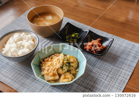A Japanese-style breakfast set with rice, miso soup, simmered tofu and eggs, and a small side dish 130072616