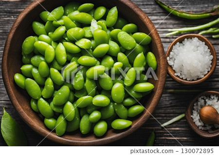 Steamed edamame, a healthy and vibrant snack, is lightly sprinkled with coarse sea salt, enhancing its natural flavor. AI Generated 130072895