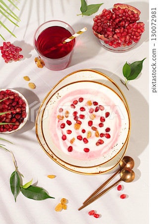 Healthy breakfast with ingredients. Pomegranate yogurt with pomegranate berries, raisins and juice on sunny table, fruit salad, detox diet and natural nutrition concept, Healthy lifestyle advertising 130072981