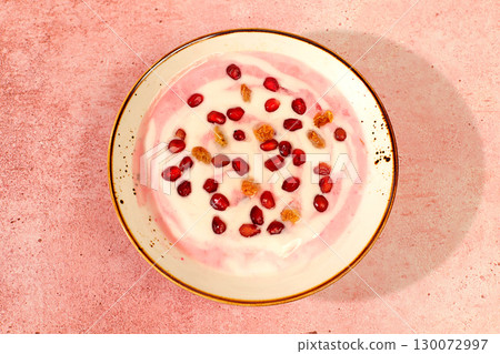 Pomegranate yogurt bowl with pomegranate pieces, raisins fresh cream for healthy eating and natural juice. Healthy breakfast with ingredients, kitchen background, Natural nutrition and diet concept 130072997