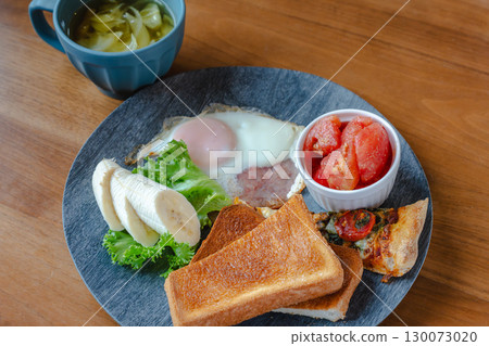 A Western-style breakfast plate with toast, fried eggs, bananas, tomatoes, and pizza. A Western-style breakfast plate with toast, fried eggs, bananas, tomatoes, and pizza. 130073020