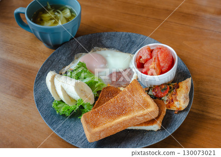 A Western-style breakfast plate with toast, fried eggs, bananas, tomatoes, and pizza. A Western-style breakfast plate with toast, fried eggs, bananas, tomatoes, and pizza. 130073021