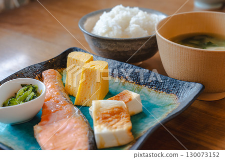 日式早餐包括烤鮭魚、玉子燒(煎蛋捲)、魚板(魚餅)、小碗米飯和味噌湯 日式早餐包括烤鮭魚、玉子燒(煎蛋捲)、魚板(魚餅)、小碗米飯和味噌湯 130073152