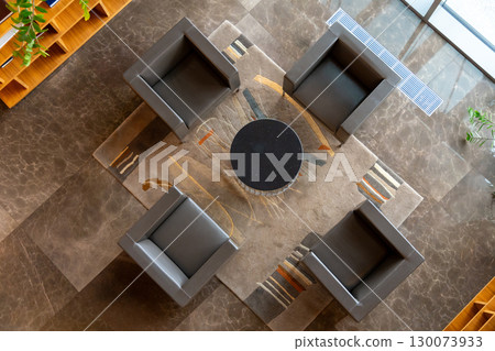 A top-down view of a modern hotel lobby meeting area with four comfortable armchairs and a table A top-down view of a modern hotel lobby meeting area with four comfortable armchairs and a table 130073933