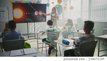 Astronomy Class: Female Teacher Explaining Solar System to Primary School Children Using Digital Screen 130075195