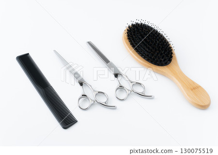 A set of hairbrush, haircutting scissors, thinning shears and comb on a white background A set of hairbrush, haircutting scissors, thinning shears and comb on a white background 130075519