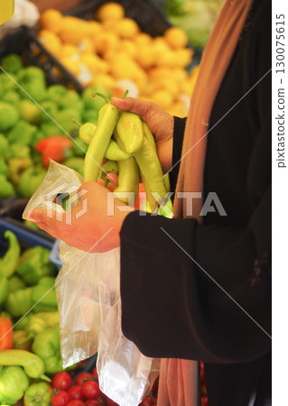 Woman selecting fresh peppers at outdoor market 130075615