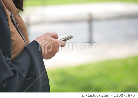 Person using smartphone while standing on green grass Person using smartphone while standing on green grass 130075670