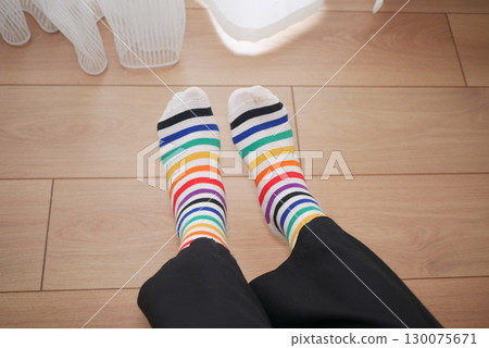 Colorful striped socks worn indoors on wooden floor Colorful striped socks worn indoors on wooden floor 130075671
