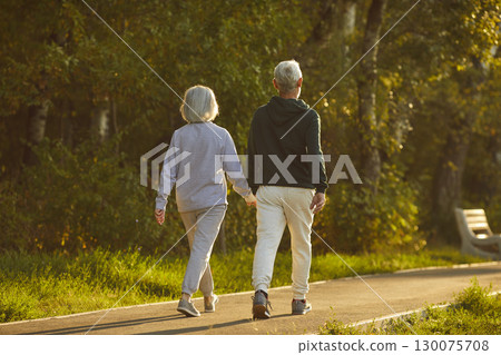 Senior couple in sportswear walking together on a path in a green park in summer 130075708