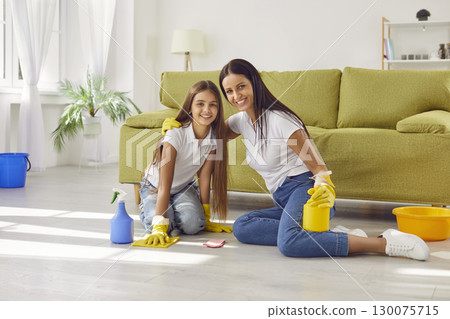 Happy smiling young mother with daughter child washing the floor in the living room at home. 130075715