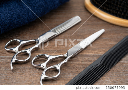 Close-up of a set of haircutting scissors, thinning shears, comb and hairbrush Close-up of a set of haircutting scissors, thinning shears, comb and hairbrush 130075993