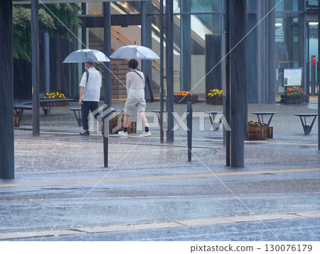 Men and women walking to work in front of Takayama Station on a rainy day 130076179