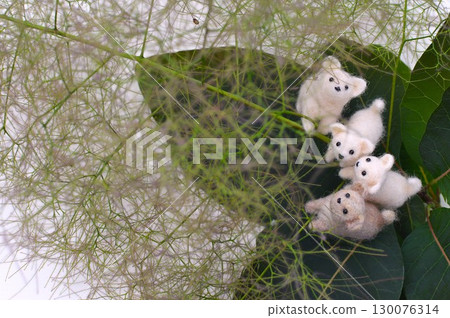 Felt puppies gathering on the blossoms of a smoke tree 130076314