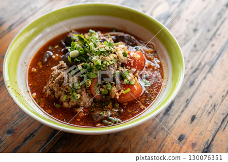 A bowl of Khanom Jeen Nam Ngeow (Northern Thai Spicy Noodle Soup) served on table. Spicy Noodle Soup is influenced by Thai-Yai, now this food is an iconic northern Thai food. 130076351