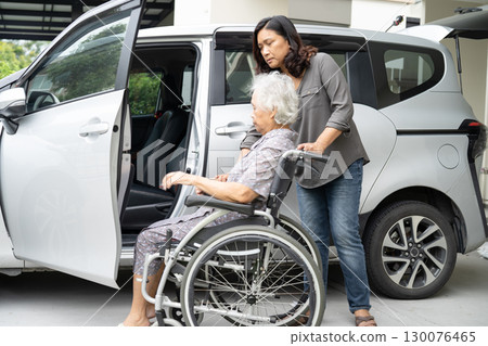 Caregiver help and support asian elderly woman sitting on wheelchair prepare get to her car to travel in holiday. 130076465