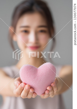 [Vertical photo] A woman holding a heart-shaped object 130077074