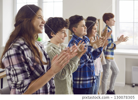 Group of happy elementary school students clapping hands celebrating together in classroom Group of happy elementary school students clapping hands celebrating together in classroom 130078305