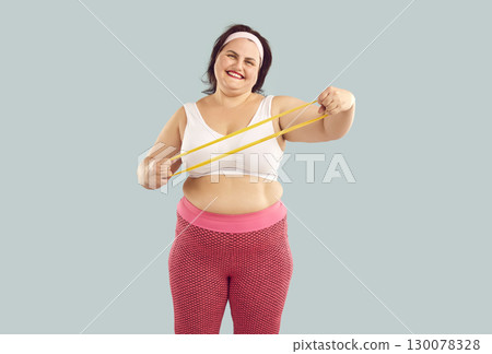 Fat funny woman doing stretching exercises with rubber band in hands on blue background. Fat funny woman doing stretching exercises with rubber band in hands on blue background. 130078328