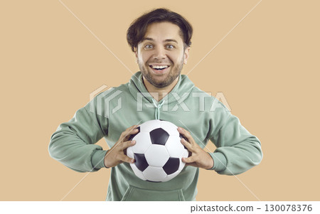 Portrait of happy, excited soccer player or sports trainer holding soccer ball and smiling 130078376