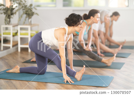 Latina stretching into Half Monkey Pose during group yoga practice Latina stretching into Half Monkey Pose during group yoga practice 130078507