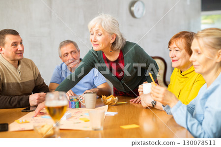 Cheerful elderly woman playing board game with friends 130078511