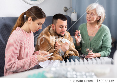 Elderly mother and a young wife give pills and medicines to her husband during illness Elderly mother and a young wife give pills and medicines to her husband during illness 130078536