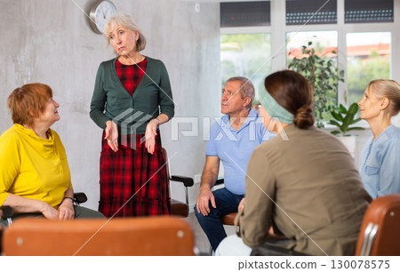 Unhappy senior woman talking during group psychological therapy 130078575