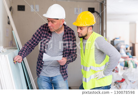 Architect discussing work with builder in construction site 130078598