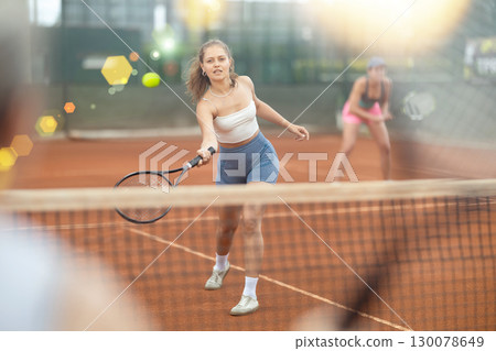 Two young women playing doubles tennis Two young women playing doubles tennis 130078649